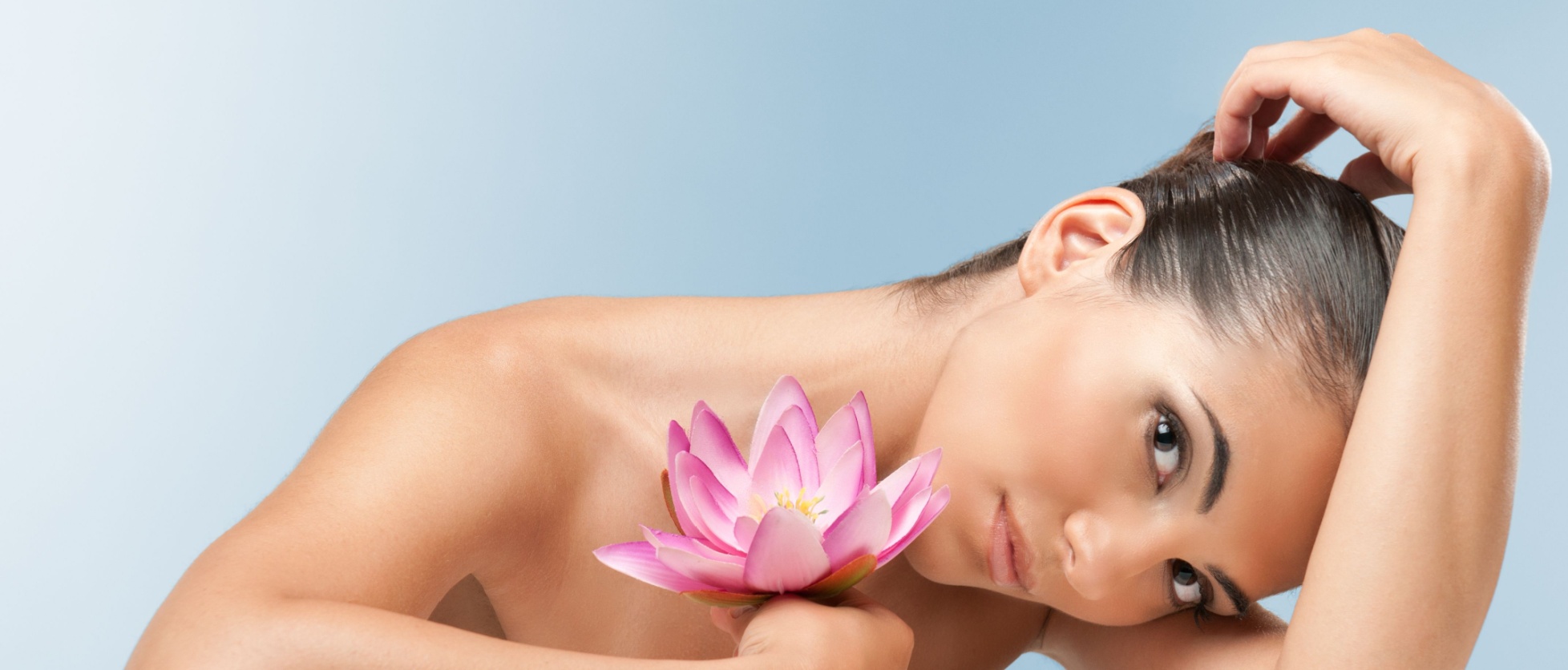 Woman with smooth skin caressing lotus flower